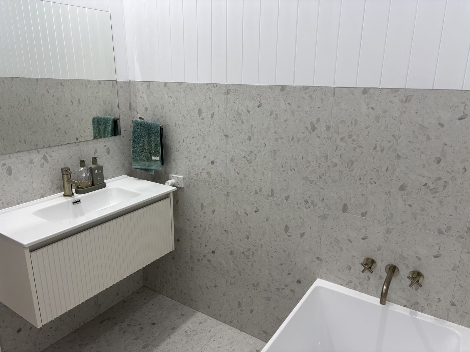 Terrazzo tile bathroom with vanity and freestanding bath